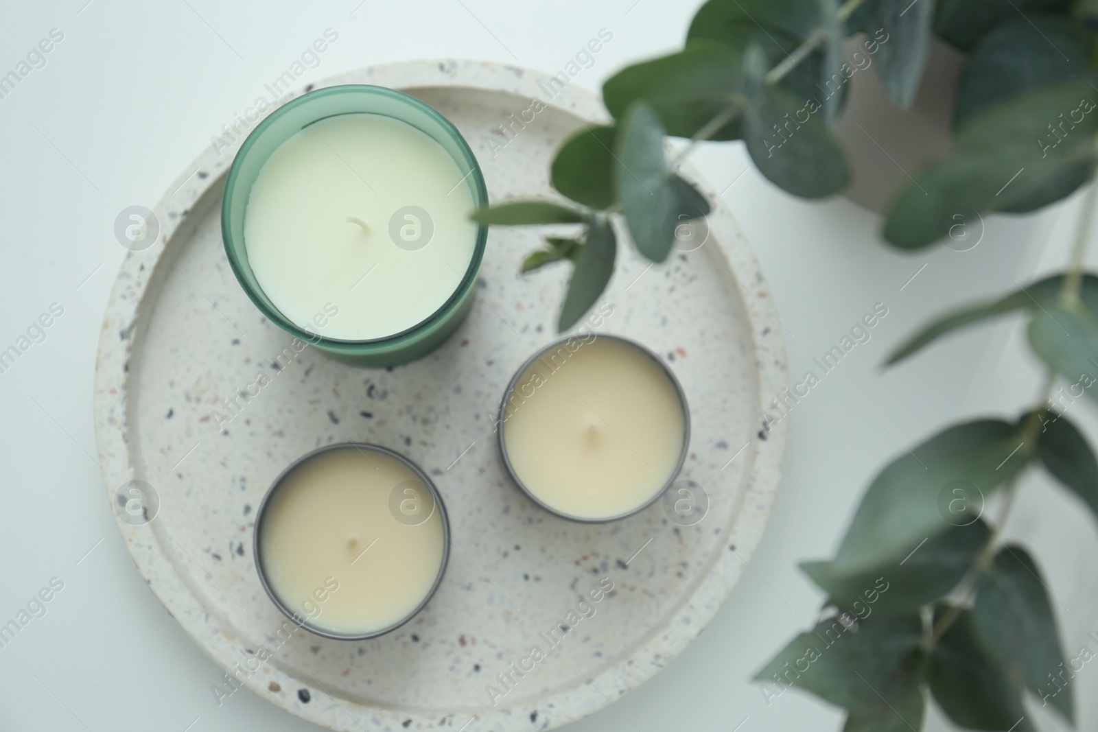 Photo of Candles and eucalyptus branches on white table, flat lay. Interior element