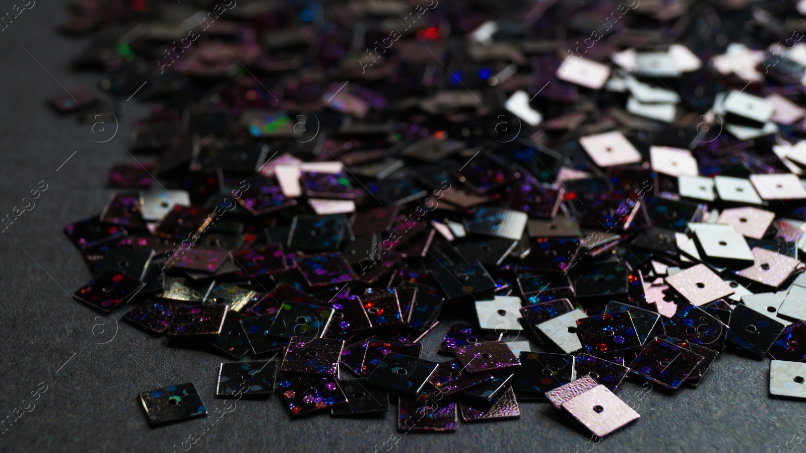 Photo of Many beautiful sequins on black background, closeup