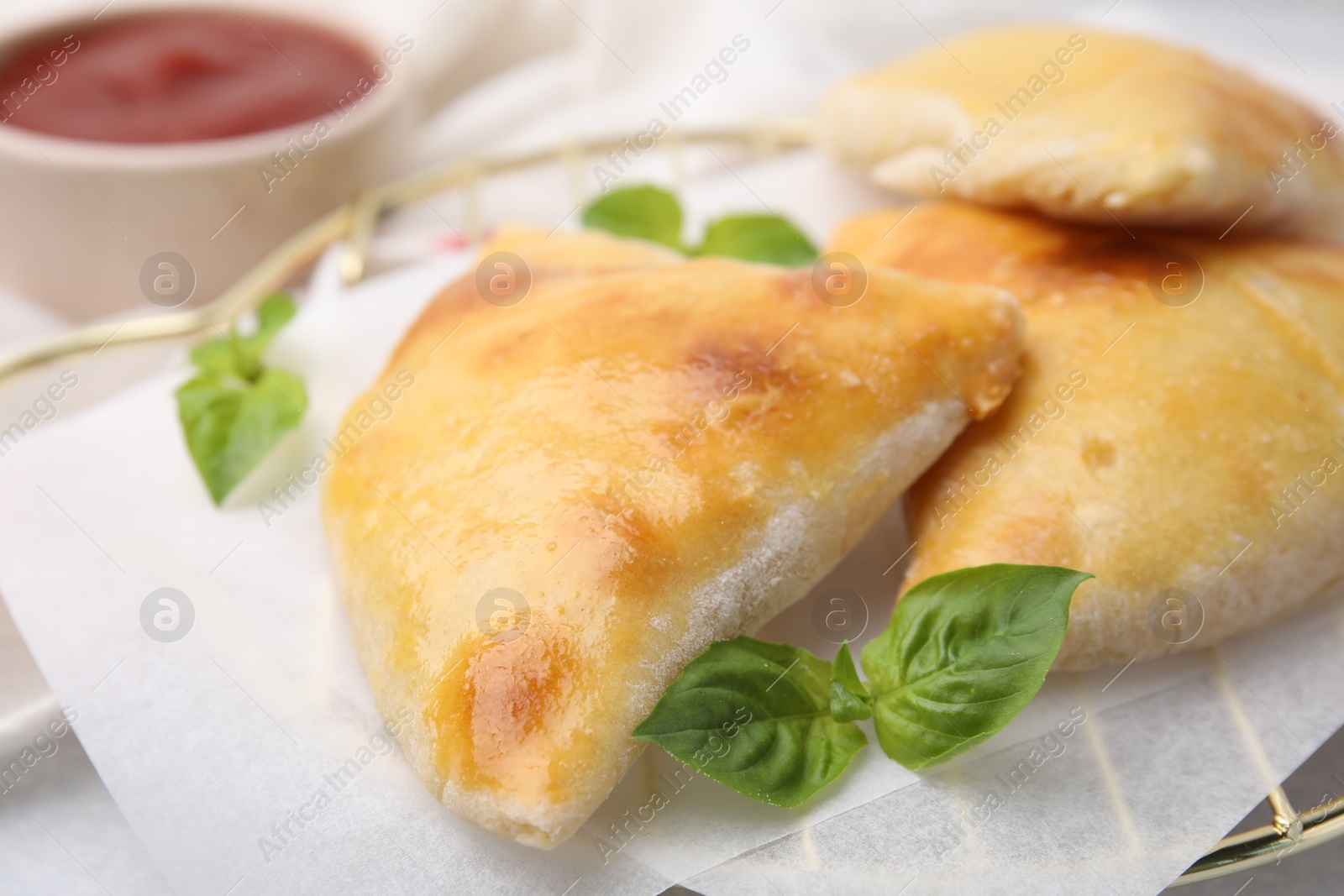 Photo of Delicious samosas and basil on white table, closeup