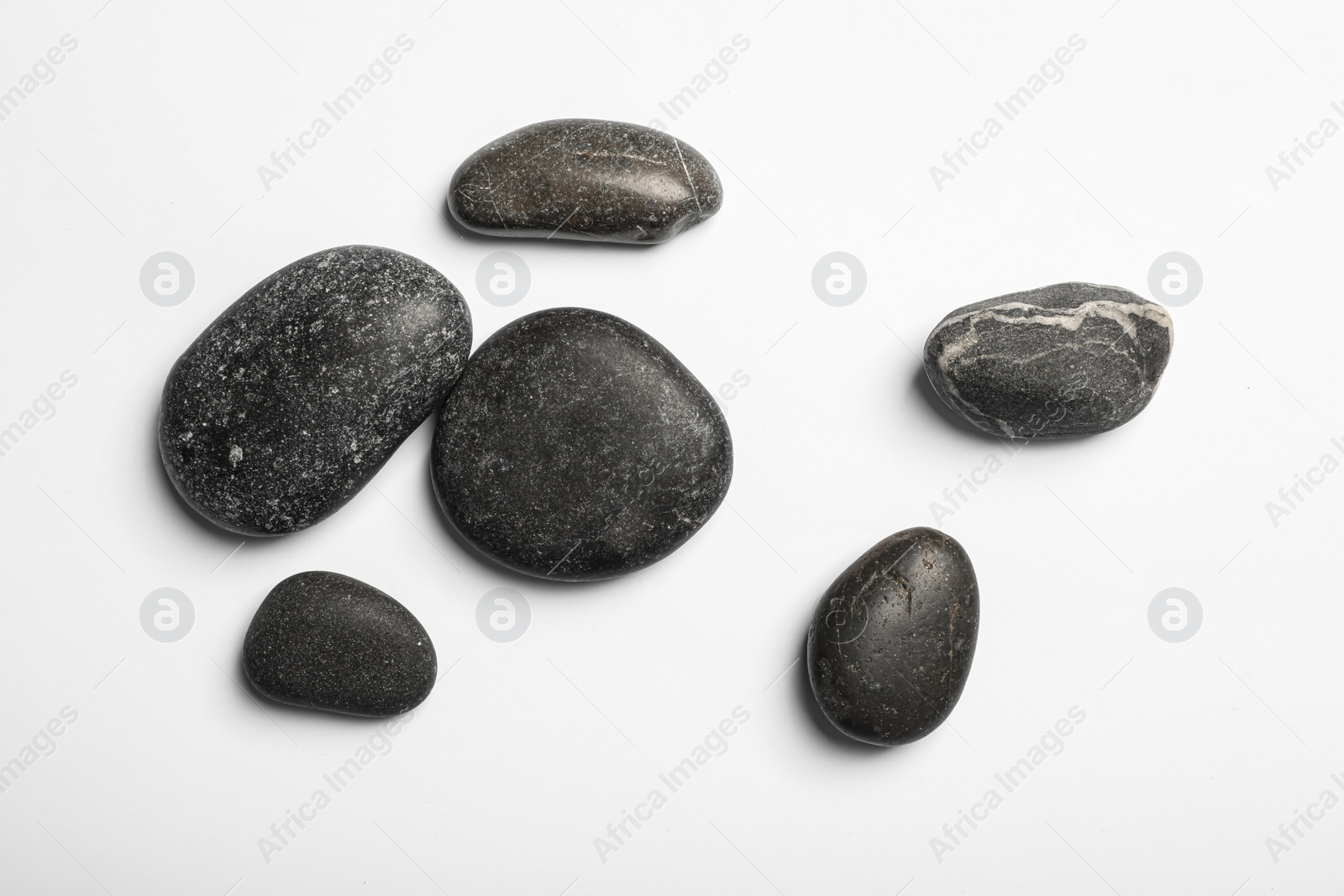 Photo of Many different stones on white background, top view