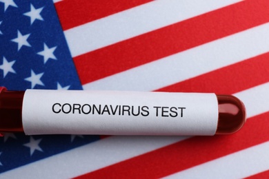 Test tube with blood sample on American flag, top view. Coronavirus pandemic in USA