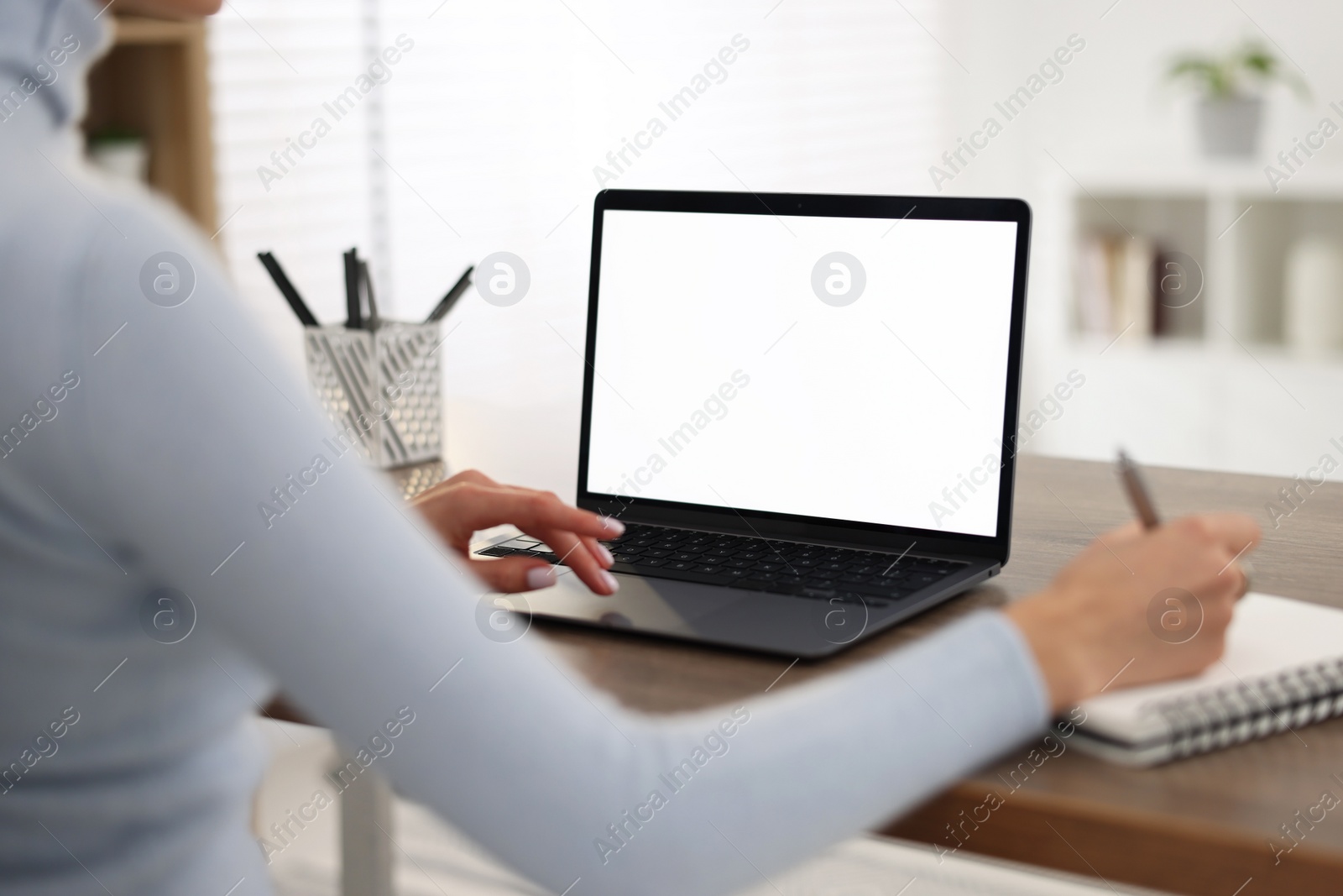 Photo of Young woman writing down notes during webinar at table indoors, closeup