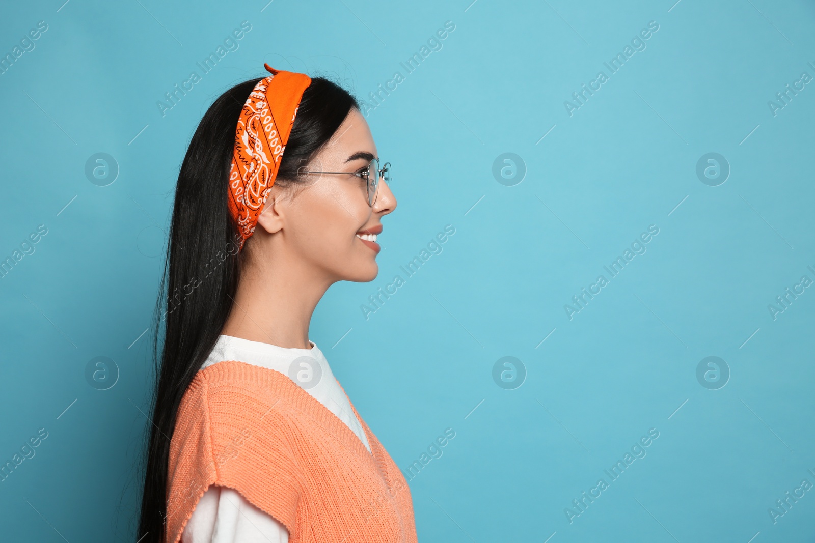 Photo of Young woman wearing stylish bandana on light blue background, space for text