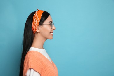 Photo of Young woman wearing stylish bandana on light blue background, space for text