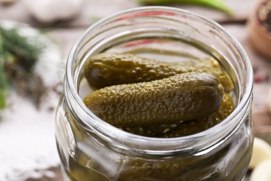 Photo of Tasty pickled cucumbers in jar on table, closeup