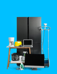 Modern refrigerator and other household appliances on blue background
