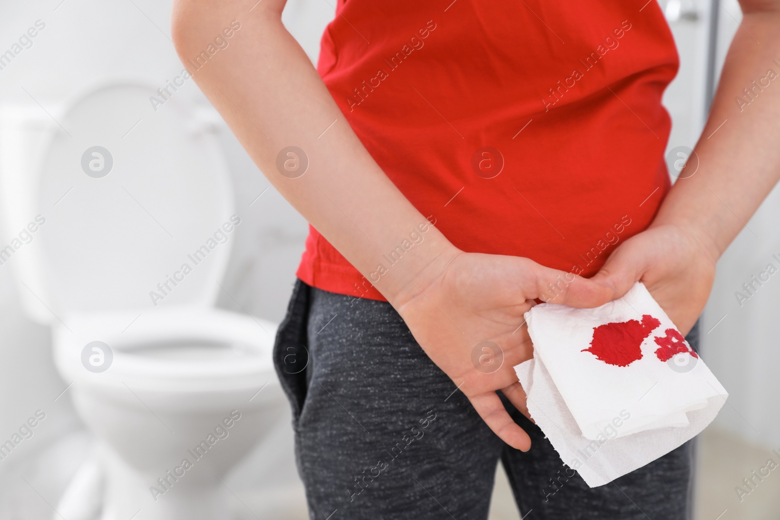 Photo of Boy holding toilet paper with blood stain in rest room, closeup. Hemorrhoid concept