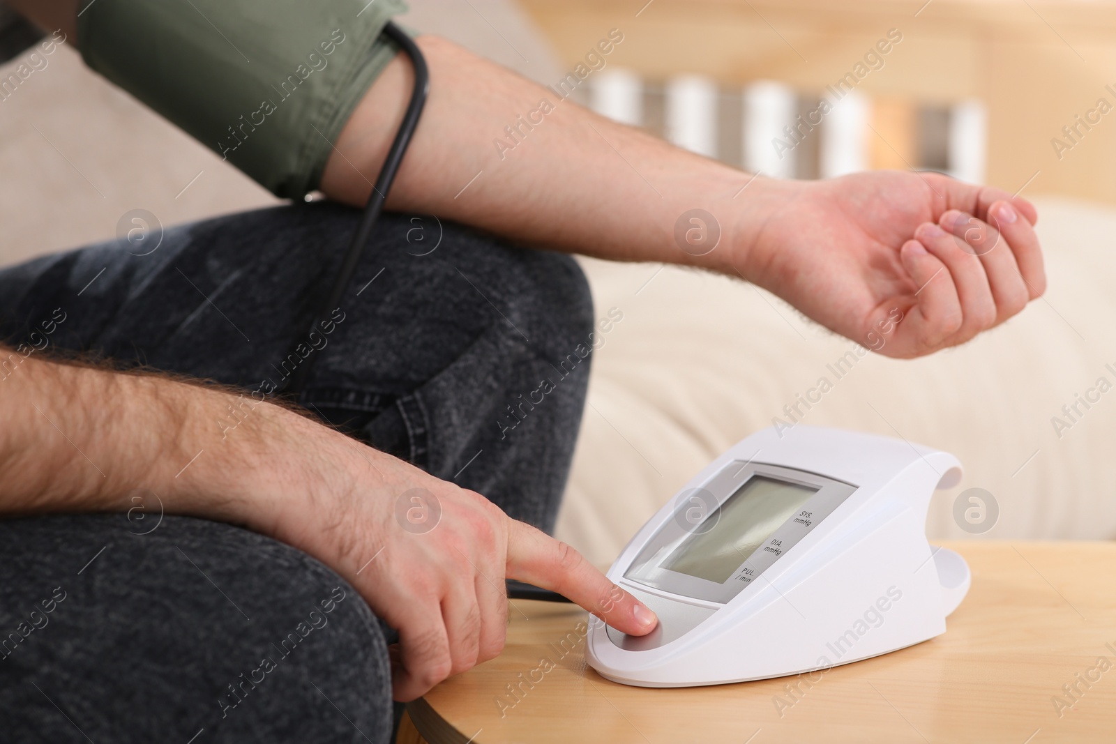 Photo of man checking blood pressure at wooden table indoors, closeup