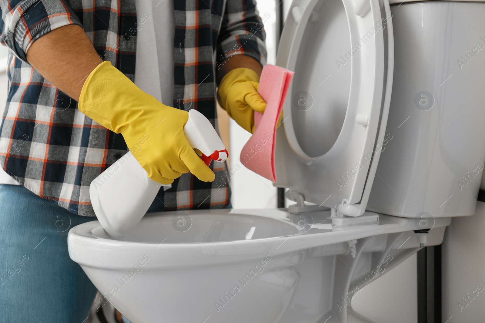 Photo of Man cleaning toilet bowl in bathroom, closeup