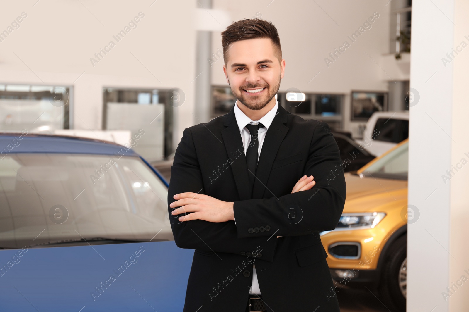 Photo of Young salesman near new car in dealership