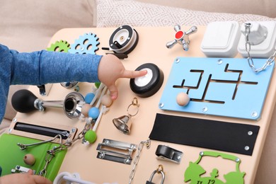 Photo of Little child playing with busy board on sofa, closeup