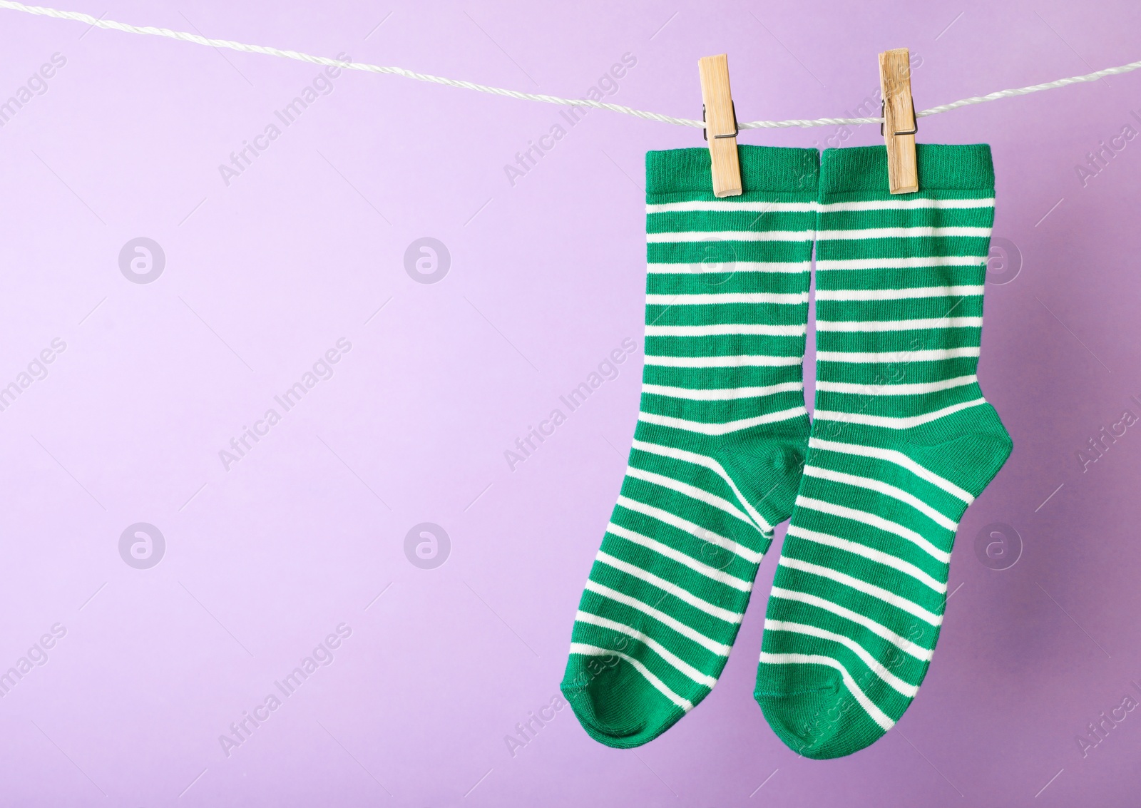 Photo of Cute child socks on laundry line against color background. Space for text