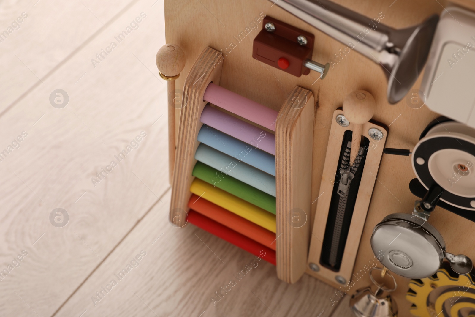 Photo of Busy board house on floor indoors, closeup view space for text. Baby sensory toy