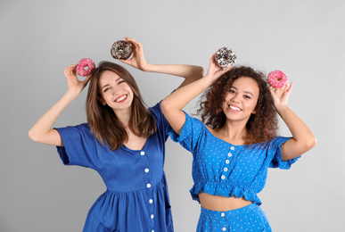 Photo of Beautiful young women with donuts on light grey background