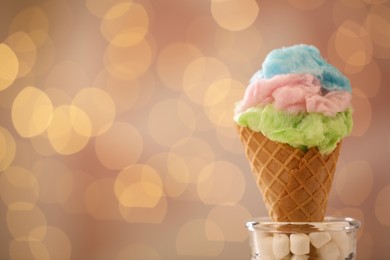 Photo of Sweet cotton candy in waffle cone against blurred lights, closeup. Space for text