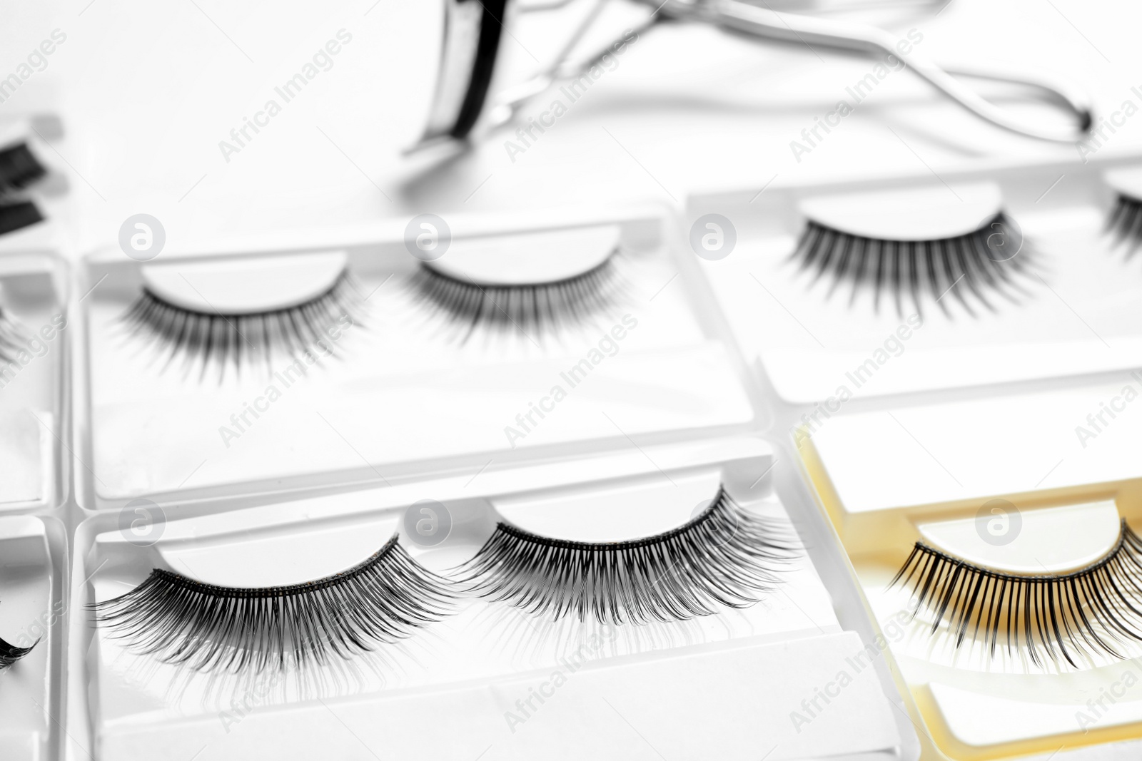 Photo of Set with different false eyelashes in packs as background, closeup