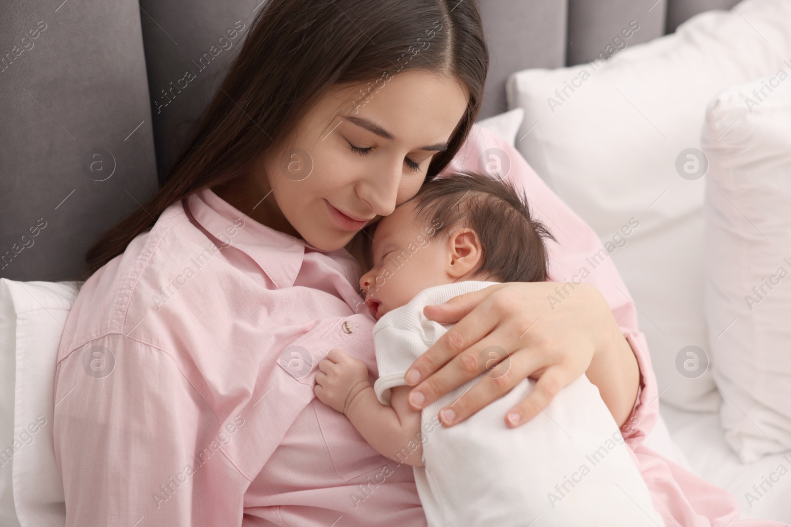 Photo of Mother with her sleeping newborn baby in bed