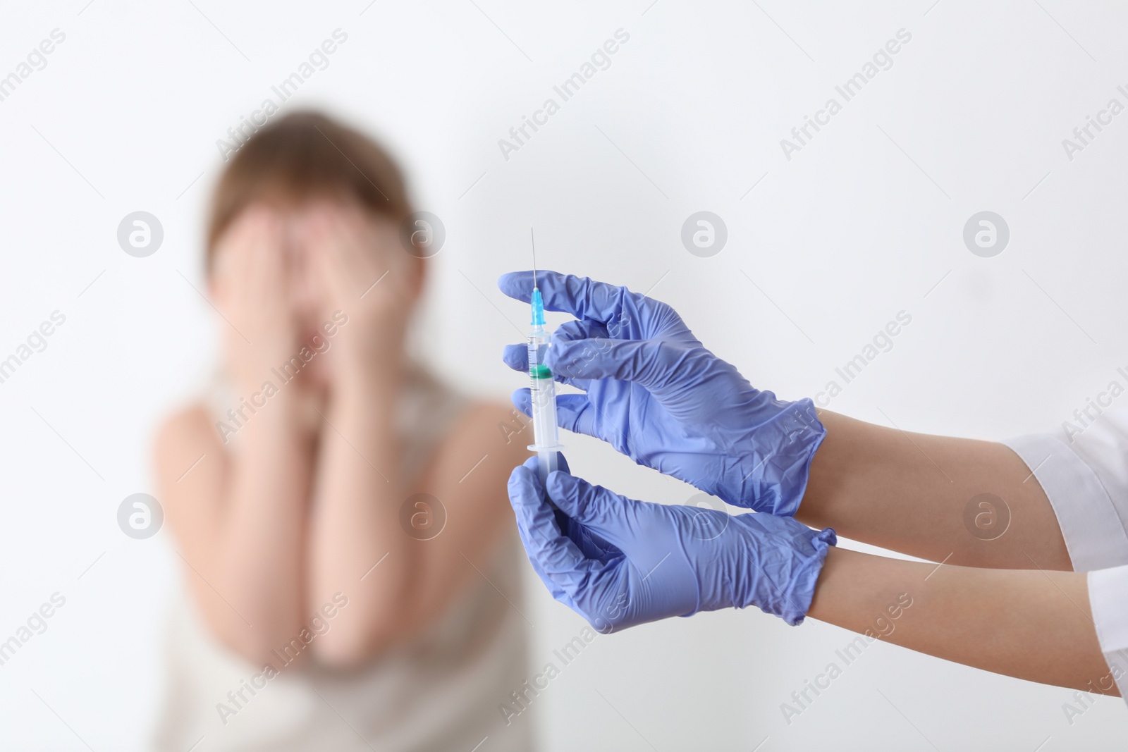 Photo of Doctor holding syringe with chickenpox vaccine and scared child on background, closeup. Varicella virus prevention