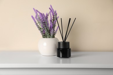 Aromatic reed air freshener and lavender flowers on white table indoors