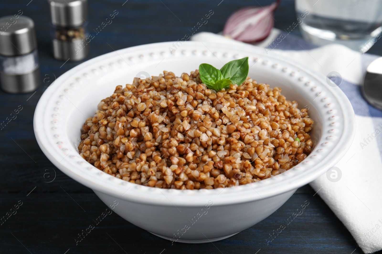 Photo of Bowl of buckwheat porridge with basil on dark table