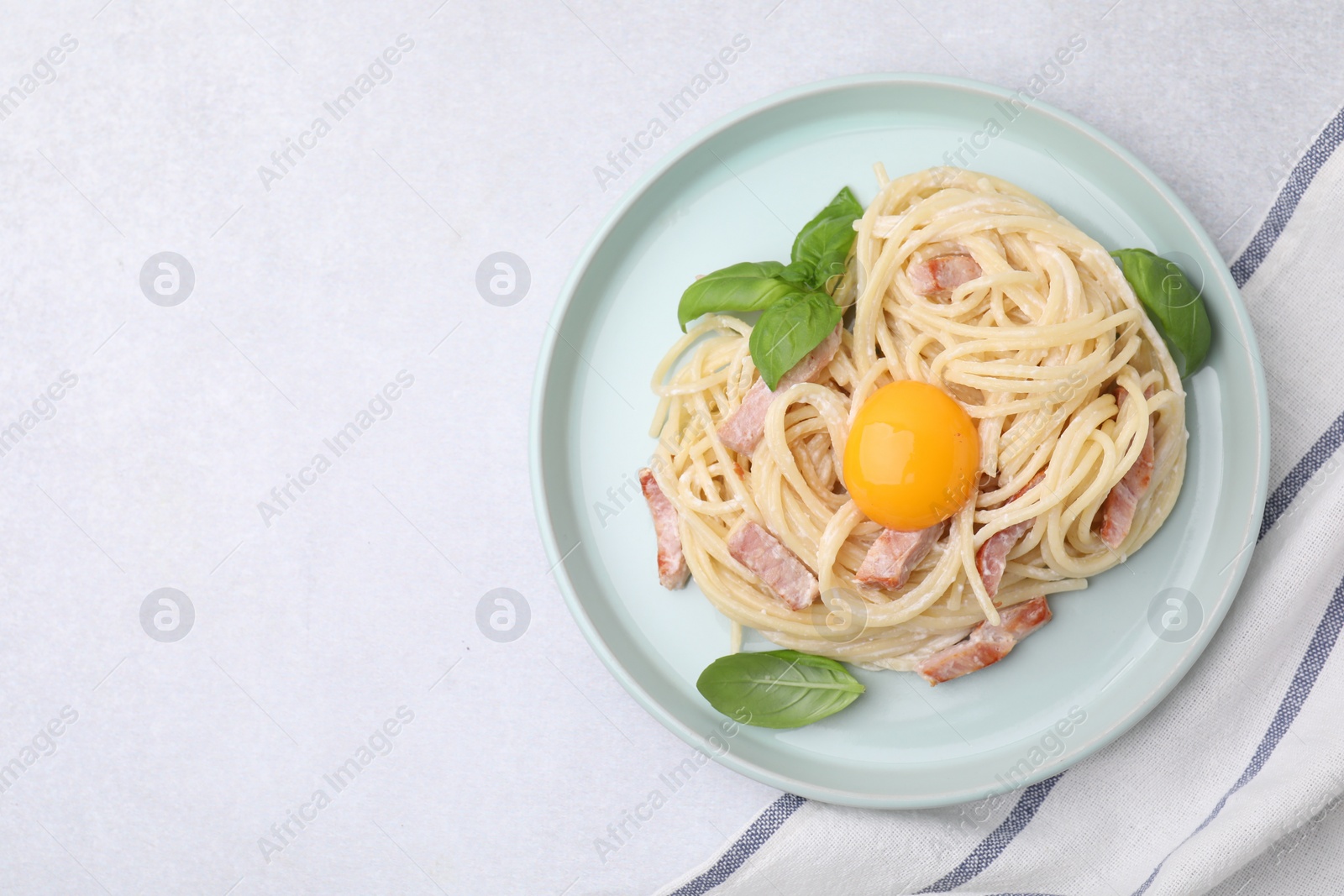 Photo of Delicious pasta Carbonara with egg yolk on white table, top view. Space for text