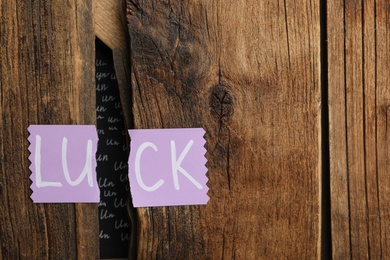 Photo of Torn card with word LUCK on wooden background. Space for text