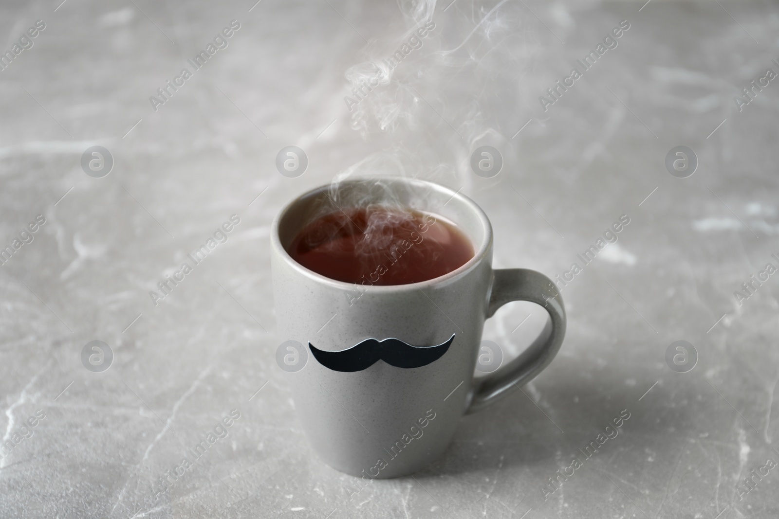 Photo of Cup with funny moustache on table. Father's day celebration