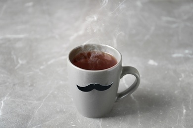 Photo of Cup with funny moustache on table. Father's day celebration