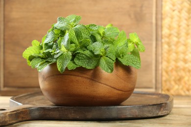 Photo of Bowl with fresh green mint leaves on wooden table