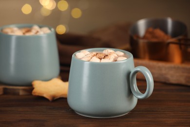 Photo of Cups of aromatic hot chocolate with marshmallows and cocoa powder on wooden table, closeup