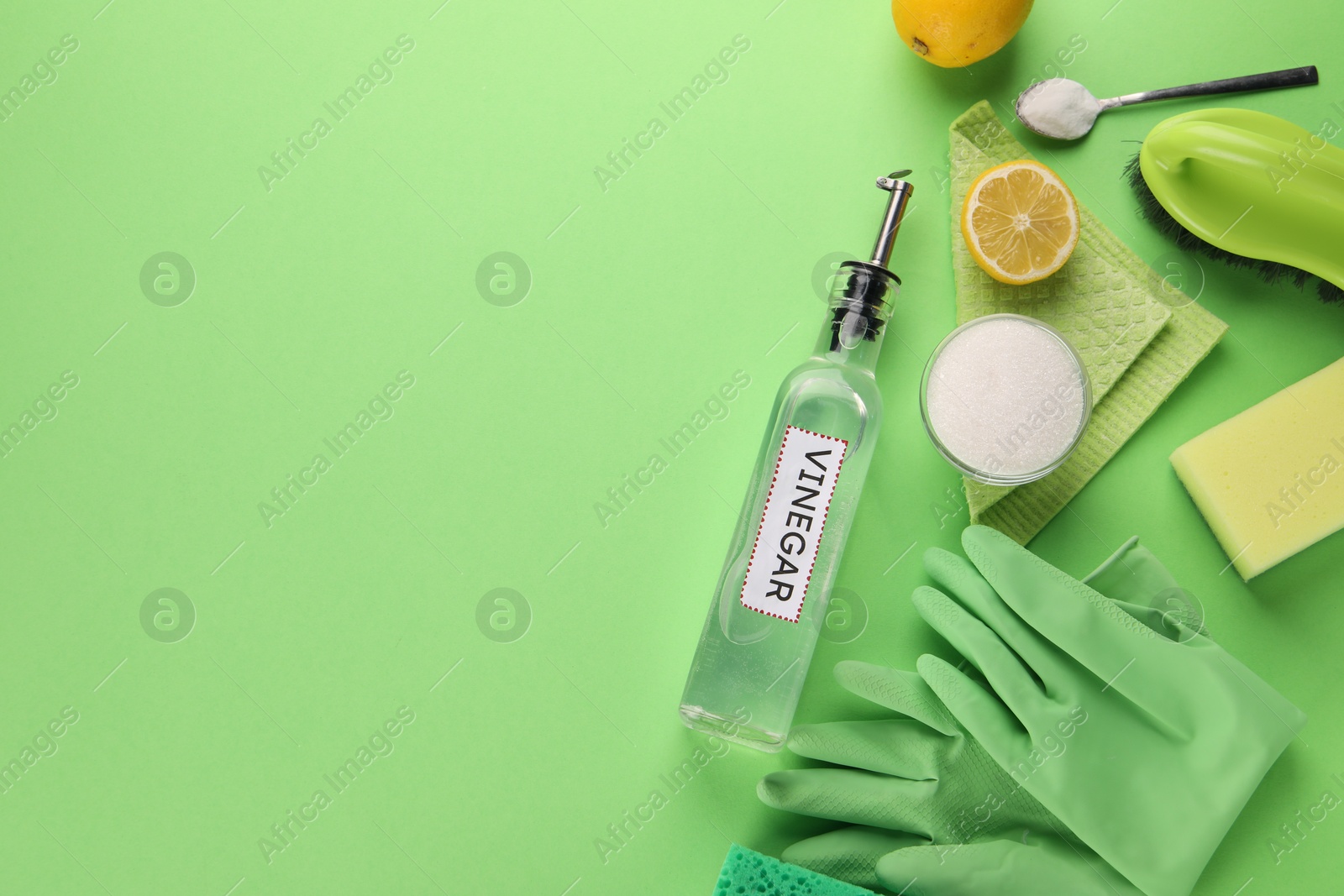 Photo of Eco friendly natural cleaners. Flat lay composition with bottle of vinegar on green background, space for text