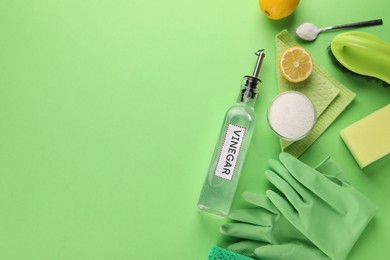 Eco friendly natural cleaners. Flat lay composition with bottle of vinegar on green background, space for text