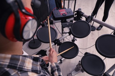 Photo of Man playing electronic drum kit during rehearsal in studio, closeup. Music band practice