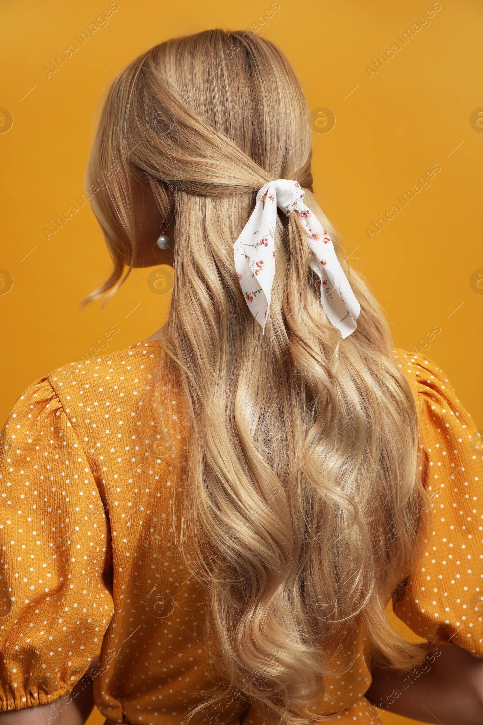 Photo of Young woman with stylish bandana on yellow background, back view