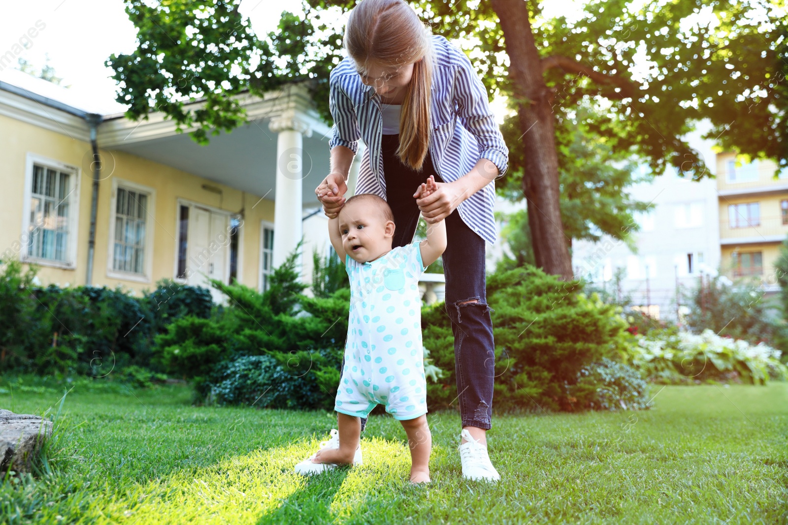 Photo of Teen nanny with cute baby on green grass outdoors