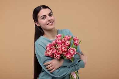 Happy young woman with beautiful bouquet on beige background