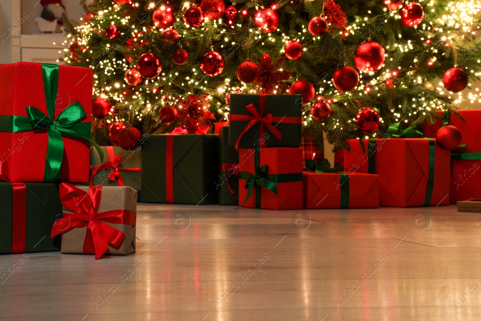 Photo of Many gift boxes near decorated Christmas tree indoors