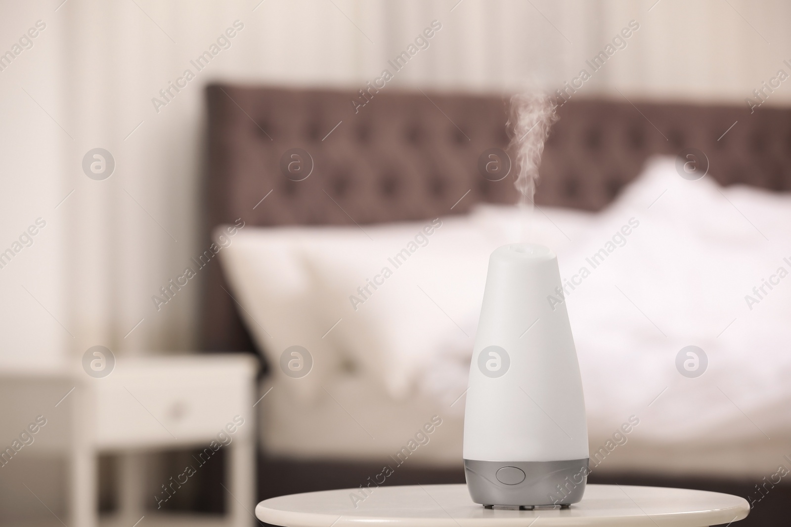 Photo of Modern essential oil diffuser on table indoors. Space for text