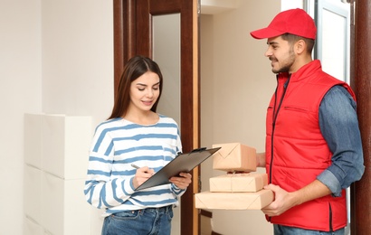 Woman receiving parcels from delivery service courier indoors