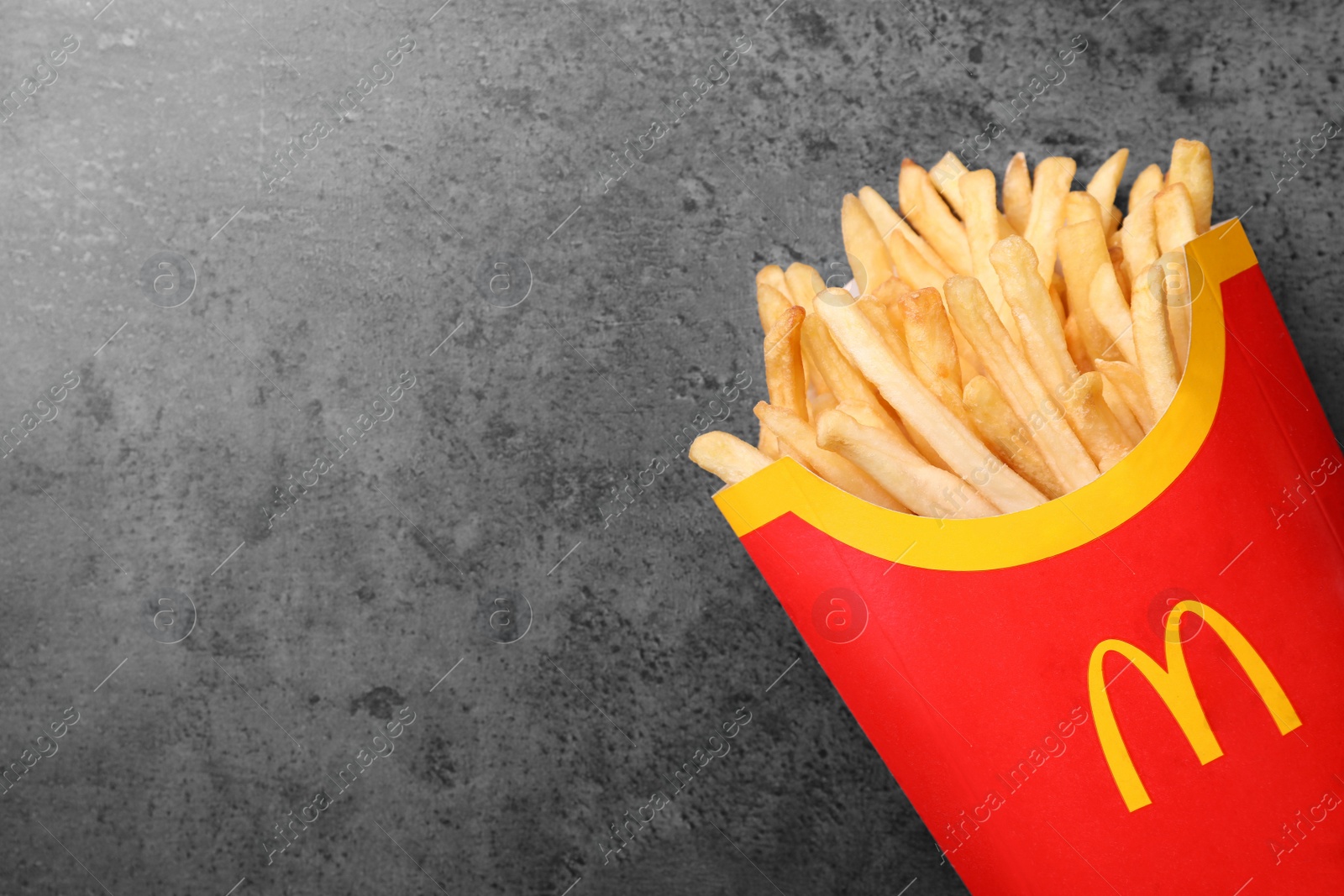 Photo of MYKOLAIV, UKRAINE - AUGUST 12, 2021: Big portion of McDonald's French fries on grey table, top view. Space for text