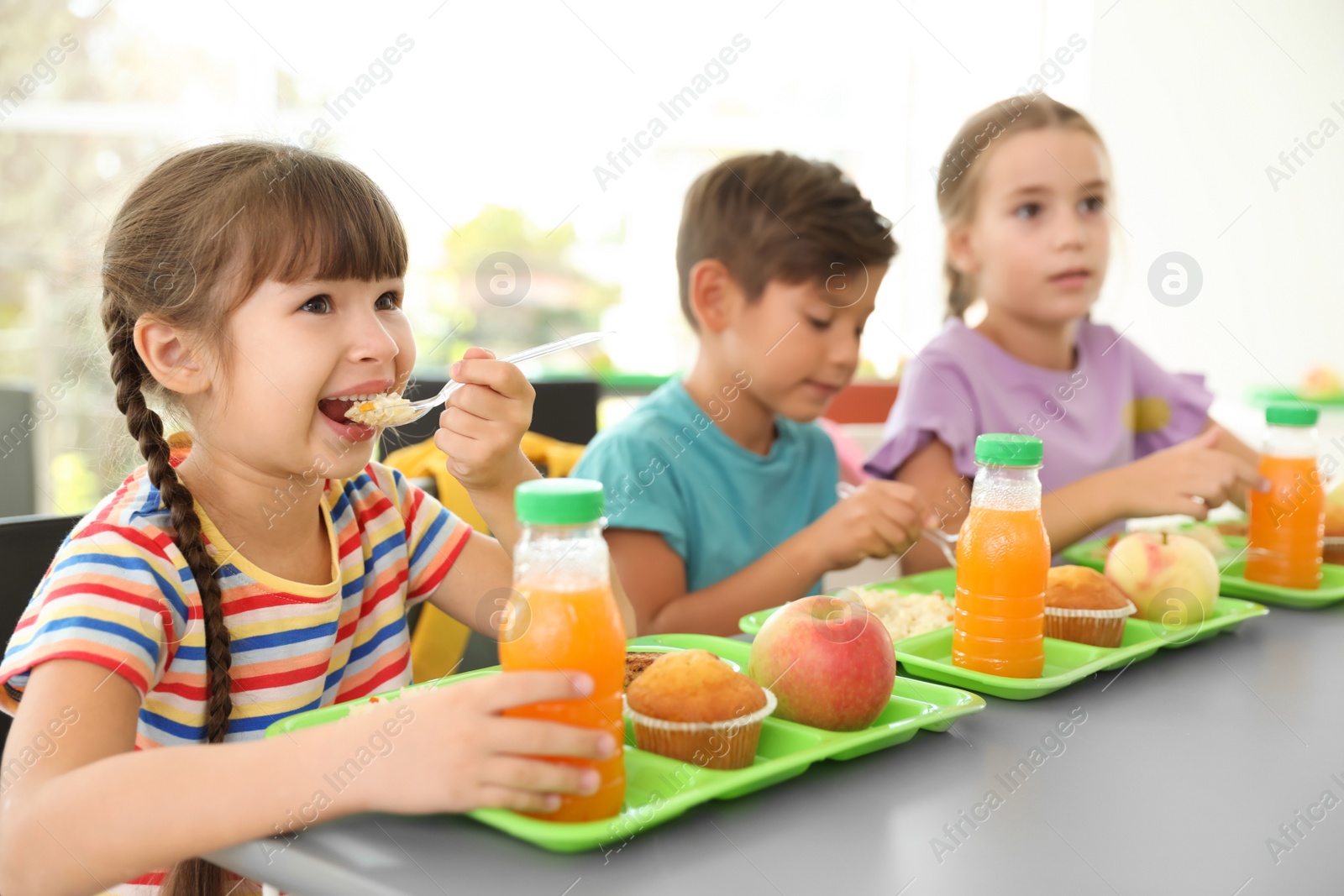 Photo of Children sitting at table and eating healthy food during break at school