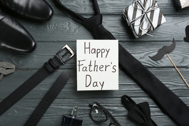 Photo of Card with phrase HAPPY FATHER'S DAY and male accessories on grey wooden background, flat lay