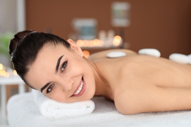 Young woman undergoing hot stone therapy in spa salon