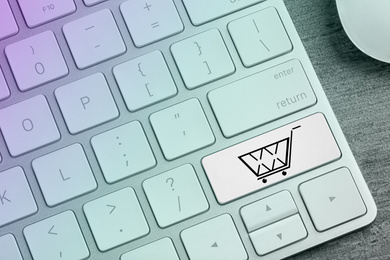 Image of Modern computer keyboard with cart symbol on table, closeup view. Internet shopping