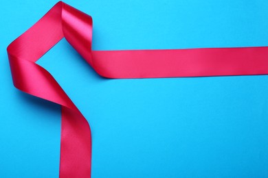 Photo of Beautiful pink ribbon on light blue background, top view. Space for text