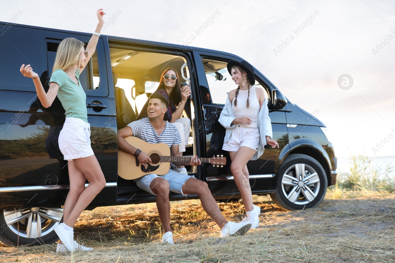 Photo of Happy friends having fun near car outdoors. Summer trip