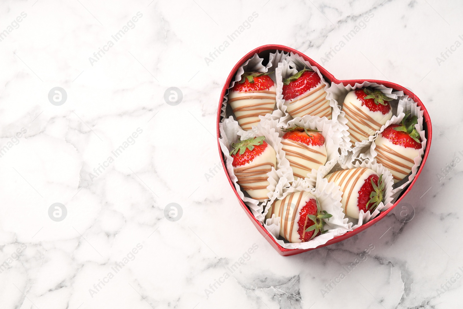 Photo of Heart shaped box with delicious chocolate covered strawberries on white marble table, top view. Space for text