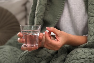 Woman with antidepressant pill and glass of water on blurred background, closeup