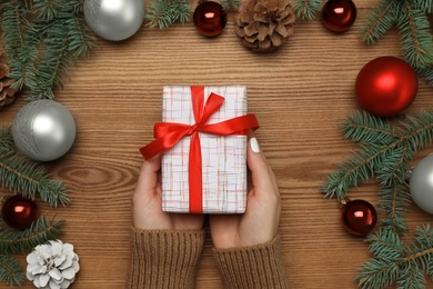 Photo of Woman with Christmas gift at wooden table, top view