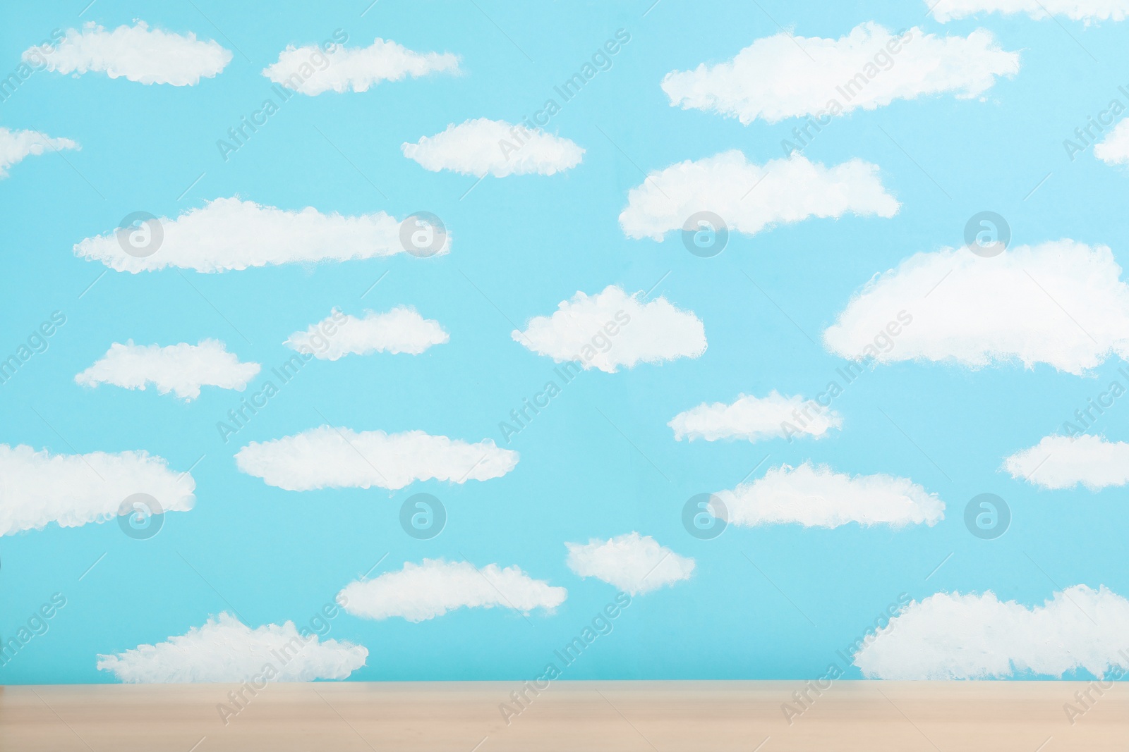 Photo of Wooden table near wall with painted blue sky. Idea for baby room interior